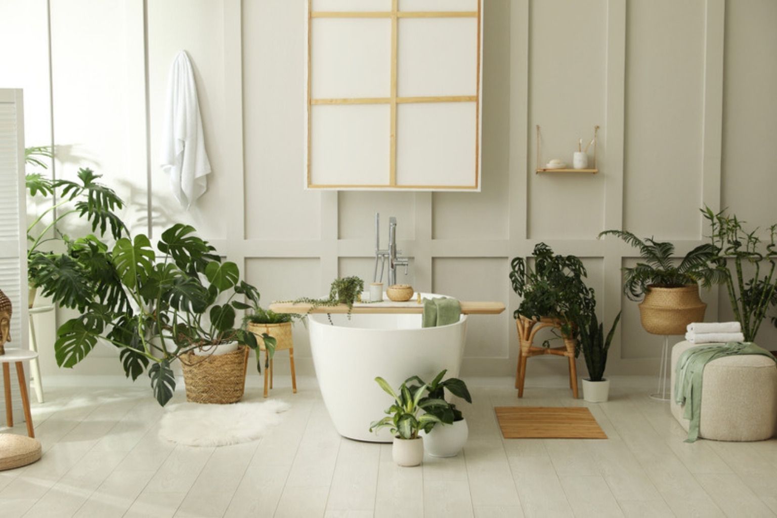 Roligt badeværelse med fritstående badekar, planter og lyse vægge i spa-stil